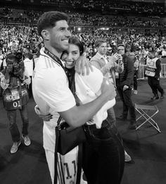 a man and woman hugging each other in front of an audience at a sporting event