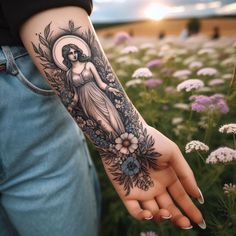 a woman's hand with a tattoo on it and flowers in the foreground