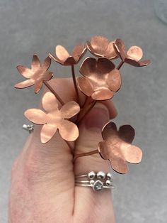 a person is holding three flower rings in their hand and they are all made out of copper