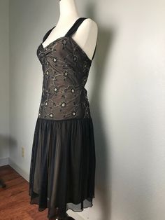 This vintage Betsey Johnson New York Collection black lace dress is stunning! It has a layer of sheer black lace over an beige under layer which gives the dress an almost chocolate brown effect. It is sleeveless with sheer lacy straps. The bodice is covered with beautiful embroidered flowers and vines. It is a size medium and made of nylon, spandex and polyester. The dress flairs below the waist line to a flattering fuller skirt. The back design is stunning! It is in very good preowned condition Sheer Sleeveless Lace Evening Dress, Sleeveless Sheer Lace Dress For Cocktail, Elegant Sheer Sleeveless Lace Dress, Brown Sheer Dress For Parties, Fitted Sleeveless Sheer Lace Dress, Brown Lace Party Dress, Sleeveless Sheer Lace Cocktail Dress, Sheer Brown Party Dress, Fitted Sheer Brown Dresses