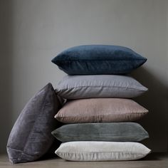 five pillows stacked on top of each other in front of a gray wall and floor