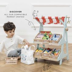 a young boy playing with toys on the floor in front of a wooden toy store