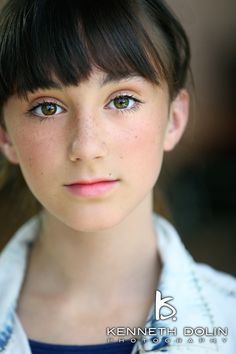 a close up of a person wearing a white shirt and black hair with brown eyes