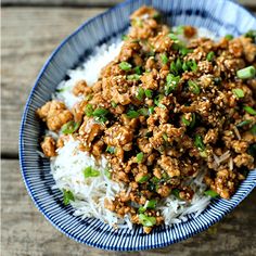 a blue and white bowl filled with rice and ground meat on top of it's side