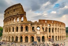 people are standing in front of an old roman collise on a cloudy day