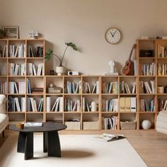 a living room filled with lots of books and furniture next to a wall mounted clock