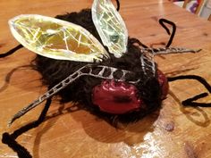 a close up of a toy insect on a wooden table with black hair and eyes