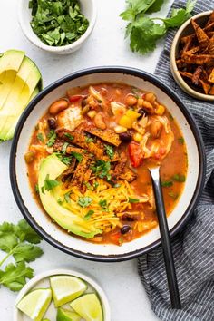 a white bowl filled with chili, beans and avocado on top of a table