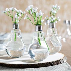 three vases with flowers in them sitting on a table