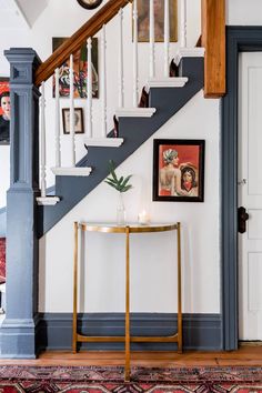 a room with stairs and pictures on the wall next to a table in front of a door