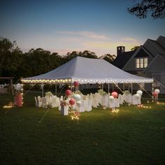 a large tent with tables and chairs set up for an event at night in front of a house