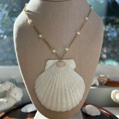 a necklace on a mannequin with a seashell and pearls hanging from it