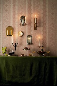 a table topped with lots of food next to wall mounted sconces and candles