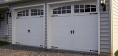 two white garage doors on the side of a house