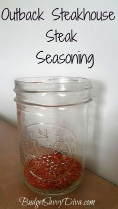 a glass jar filled with red seasoning sitting on top of a table