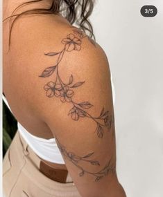 a woman's arm with flowers on it and the back of her shoulder is shown