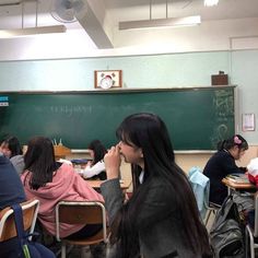 students are sitting at desks in front of a blackboard