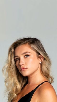 a woman with long blonde hair wearing a black tank top and looking at the camera