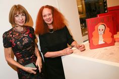 two women standing next to each other in front of paintings