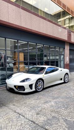 a white sports car parked in front of a building