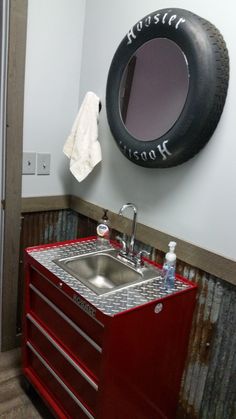 a bathroom with a sink, mirror and tire hanging on the wall next to it