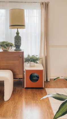 a living room with wooden floors and white curtains on the windowsill, two planters are