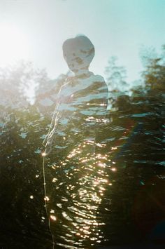 a person standing in front of some trees with the sun shining through their hair and body