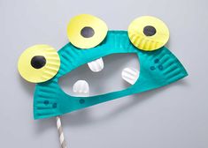 a paper plate monster mask with two eyes and a candy stick sticking out of it