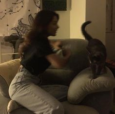 a woman sitting on top of a couch next to a cat