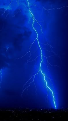 a lightning bolt is seen in the sky above a city at night time, with bright blue lighting