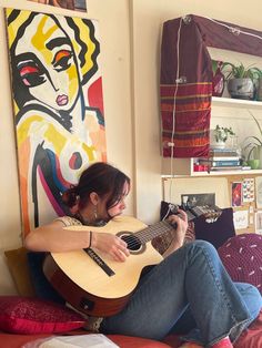 a woman sitting on top of a bed holding a guitar