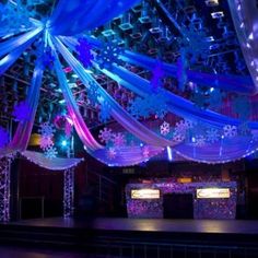 a stage set up for a party with snowflakes on the ceiling and draping