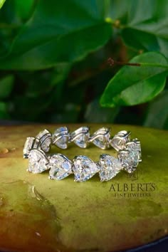 a close up of a ring on top of a green leafy surface with leaves in the background