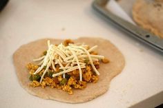 a tortilla topped with cheese and other toppings on top of a counter