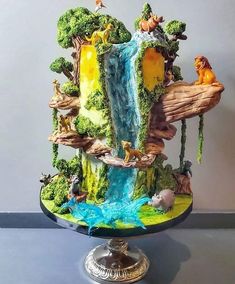 the cake is made to look like a waterfall with animals and trees on it,