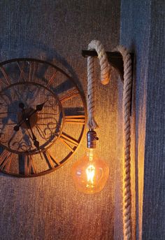 a light bulb is hanging on the wall next to an old fashioned clock and rope