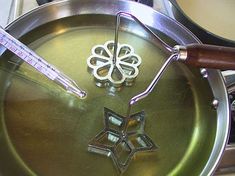 a metal pan with some scissors in it on top of a stove burner next to a thermometer