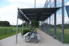 two benches under an awning at a baseball field