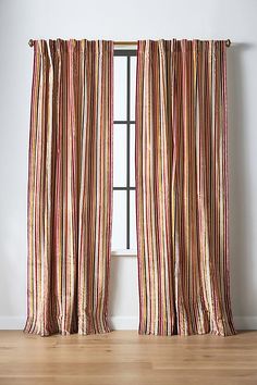 a striped curtain hanging on the side of a window in a room with hardwood floors