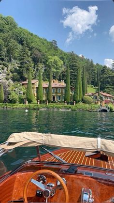 the steering wheel and dashboard of a sailboat in front of a house on a lake