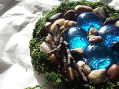 there is a blue glass ball in the center of some rocks and grass on top of sand