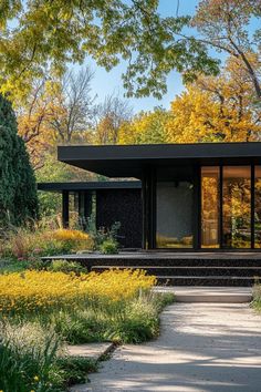 a black house surrounded by trees and flowers