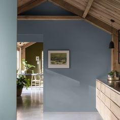 an open kitchen with blue walls and wooden beams on the ceiling, along with potted plants