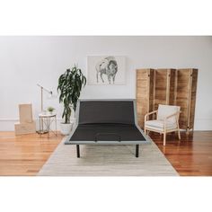 a black bed frame sitting on top of a wooden floor next to a white chair