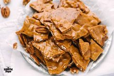 a plate full of pecans and caramel brittleers on a white table cloth