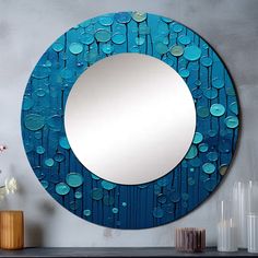 a round blue mirror sitting on top of a table next to a vase with flowers