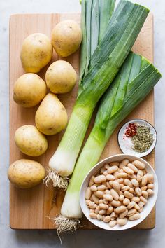 potatoes, celery, and beans are laid out on a wooden cutting board