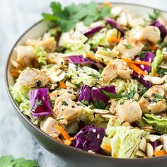 a salad with chicken, lettuce and carrots in a bowl on a table