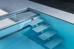 an empty swimming pool with blue water and steps leading up to the side wall,