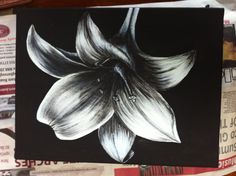 a black and white drawing of a flower on top of some newspaper paper with other papers in the background